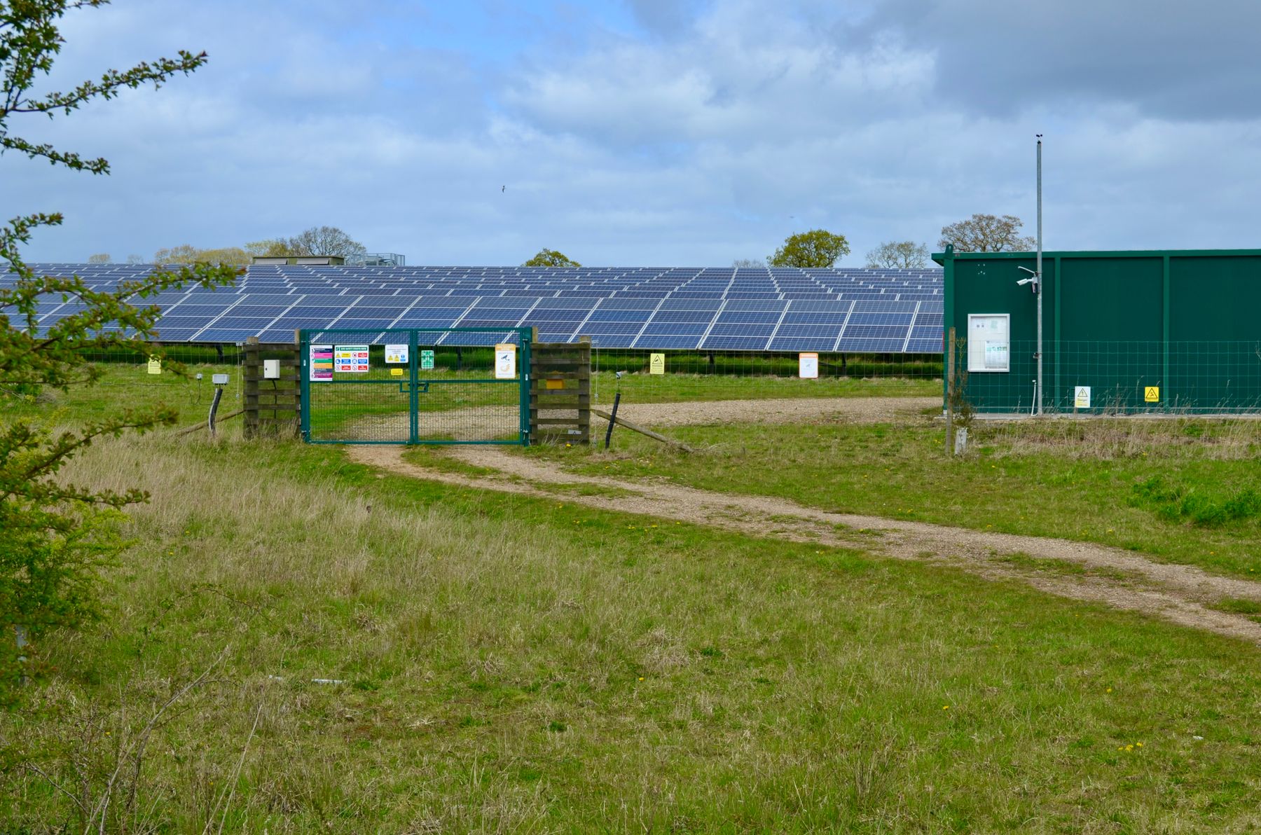A solar power station in open farmland under a clouded sky